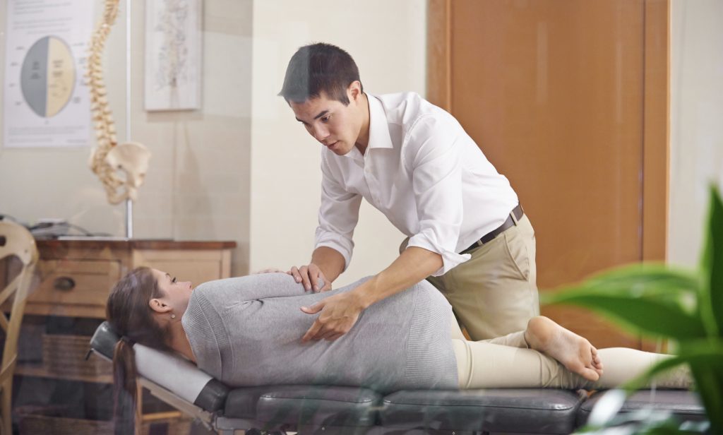 Shot of a chiropractor adjusting a young woman's spine